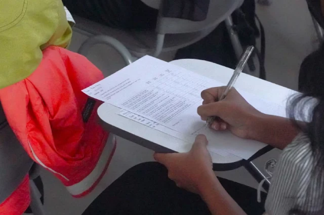 A young student answering questions on an exam paper